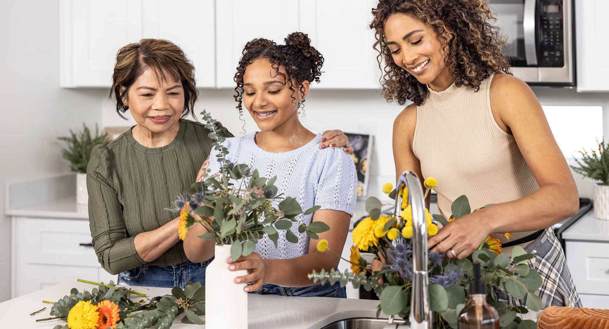 Three women arranging flowers together in a bright kitchen — Discover step